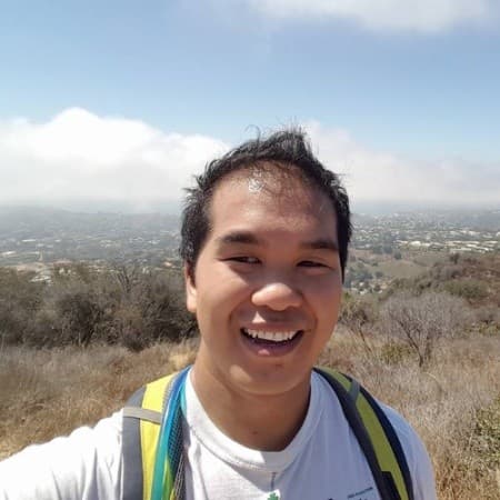 Ben Junya smiling on a hillside trail, hazy hills behind him